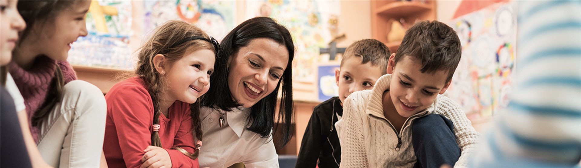Eine Erzieherin zeigt Kindern, die viel Spaß haben, etwas auf dem Boden
