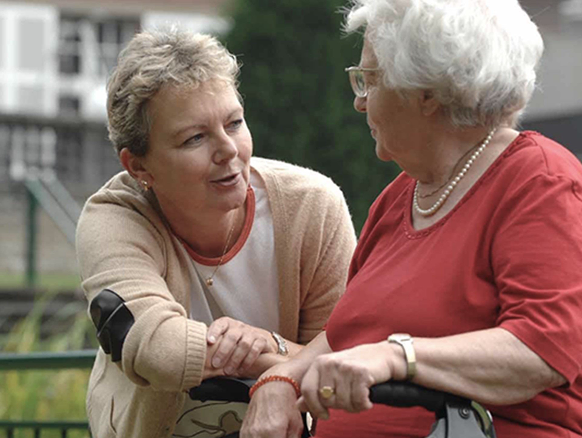 Begleiterin im Gespräch mit älterer Dame mit Rollator