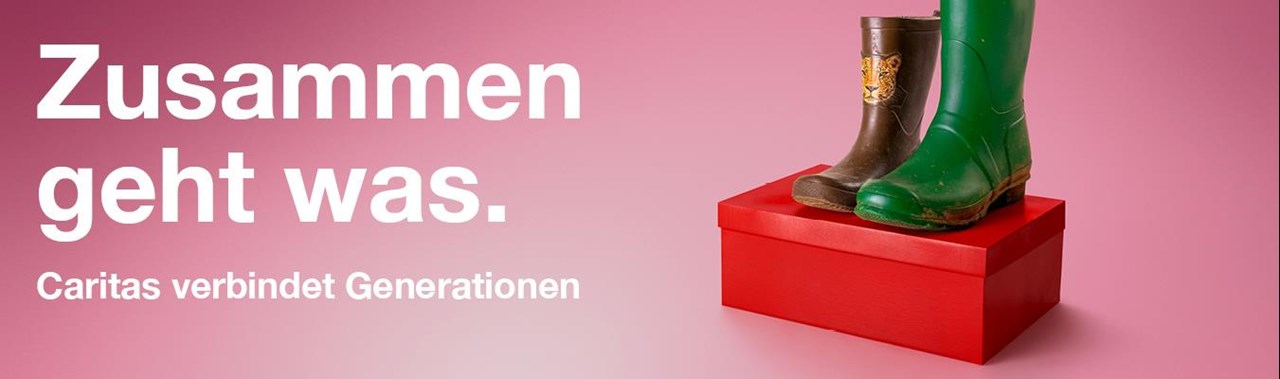 Auf einem roten Schuhkarton sind vor einem rosa Hintergrund ein Paar Gummistiefel zu sehen. Der linke Schuh ist ein brauner Kindergummistiefel mit einem Tigerkopf in kleiner Schuhgröße, der rechte ein hoher grüner Gummistiefel in großer Schuhgröße. Darüber steht das Kampagnenmotto: Zusammen geht was. Caritas verbindet Generationen.