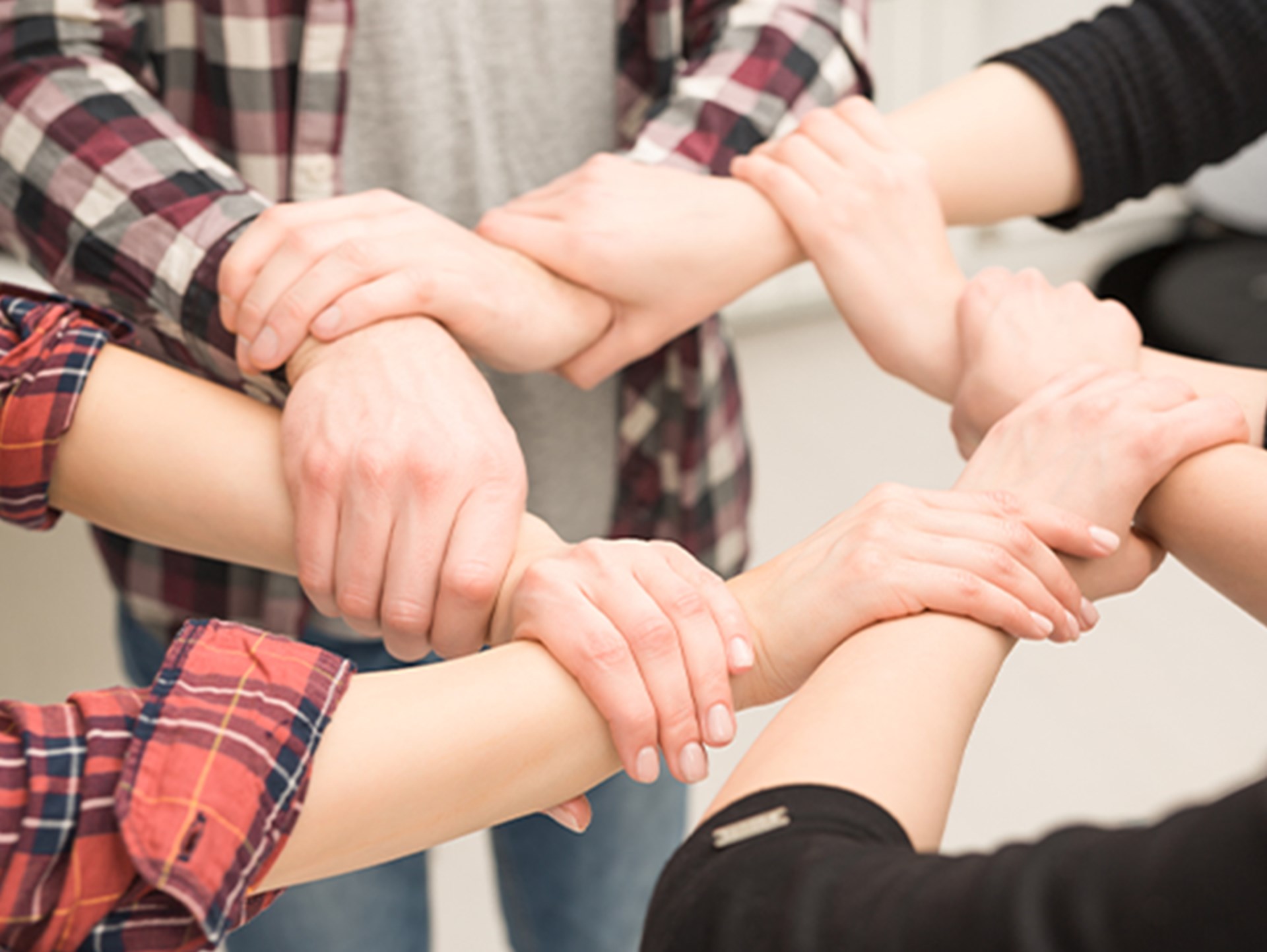Eine Gruppe von jungen Leuten halten ihre Hände in einem Ring zusammen.