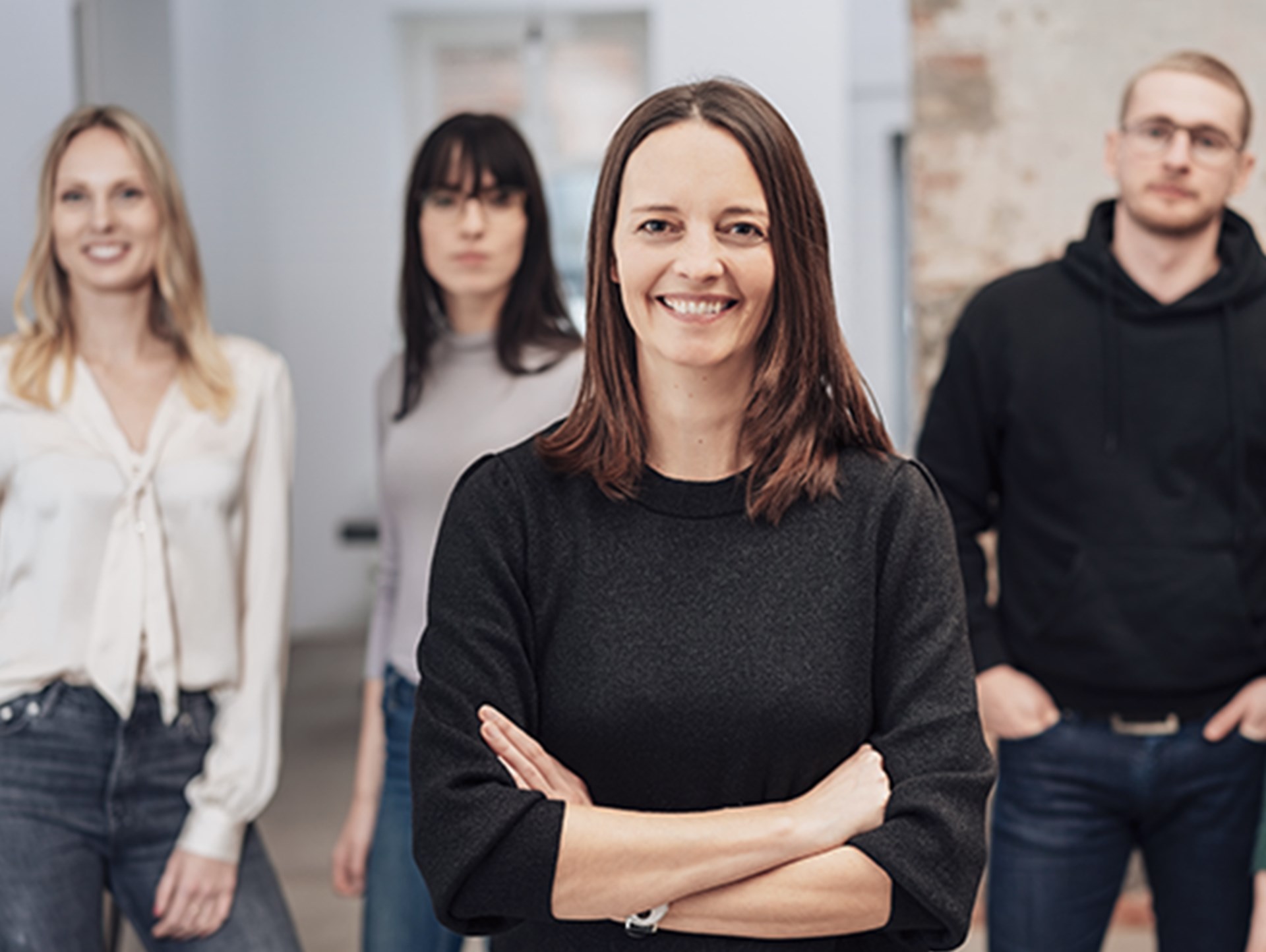 Eine Gruppe Menschen lächelt in die Kamera. Nur die Dame ganz vorne ist klar zu erkennen. Die drei Personen im Hintergrund sind unscharf.