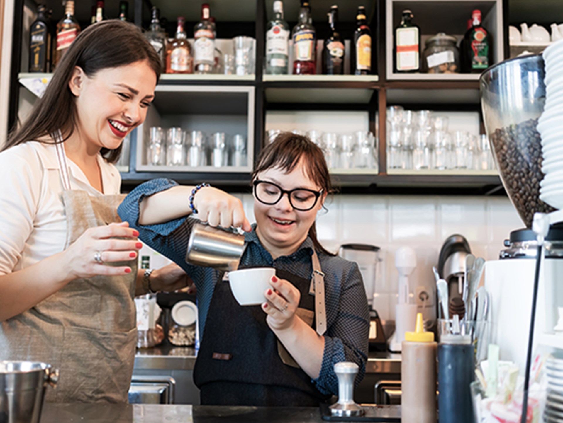 Junge Frau mit Down-Syndrom bei der Kaffeezubereitung im Café