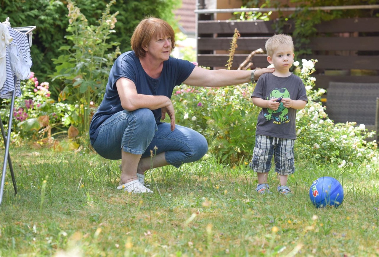 Familienpflegerin spielt mit kleinem Jungen im Garten